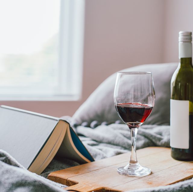 glass of wine on a board next to an opened book