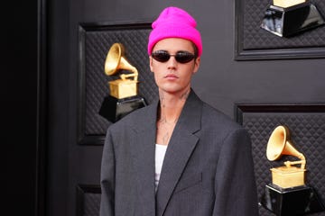 justin bieber poses in sunglasses wearing pink hat and gray suit