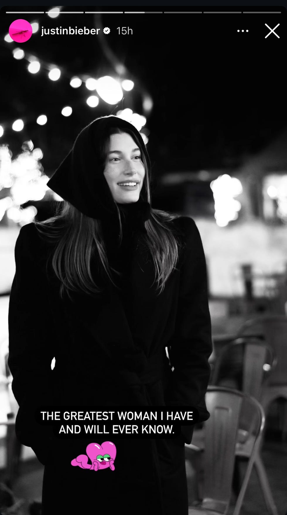 a woman standing in a cozy outdoor setting with decorative lights in the background