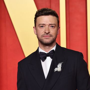 justin timberlake looks at the camera, he weras a black suit jacket and bowtie with a white collared shirt and brooch on his lapel