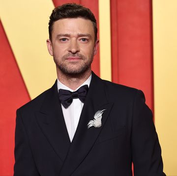 justin timberlake looks at the camera, he weras a black suit jacket and bowtie with a white collared shirt and brooch on his lapel