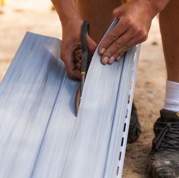 a construction worker cutting through vinyl siding using heavy duty shears in ontario canada