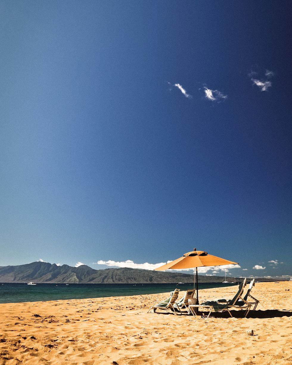 chairs and umbrella on beach with mountains in the background