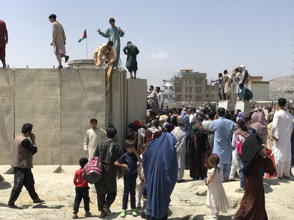 people struggle to cross the boundary wall of hamid karzai international airport to flee the country after rumors that foreign countries are evacuating people even without visas, after the taliban over run of kabul, afghanistan, 16 august 2021  photo by strnurphoto via getty images