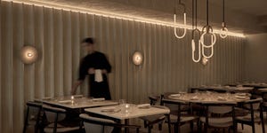 a person standing in a room with tables and chairs