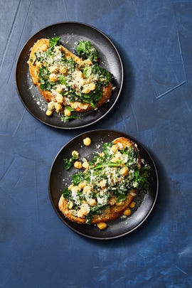 kale and chickpea toasts on black plates