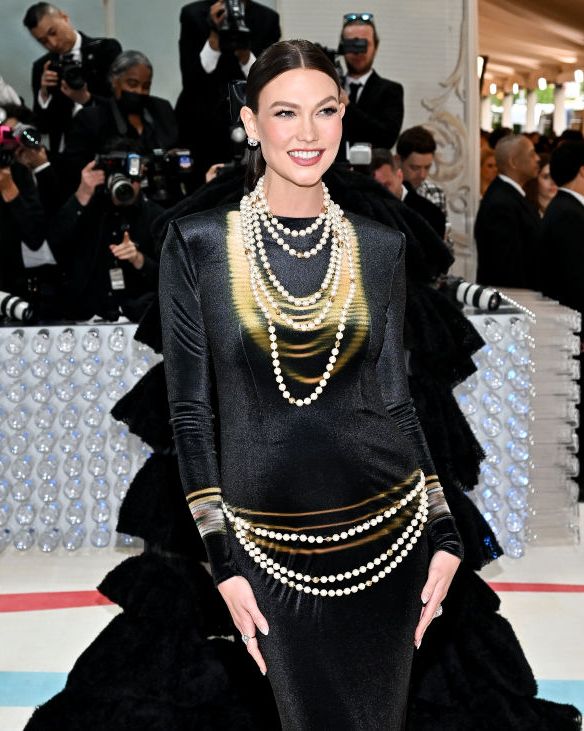 karlie kloss wearing a black column dress and adorned in pearls