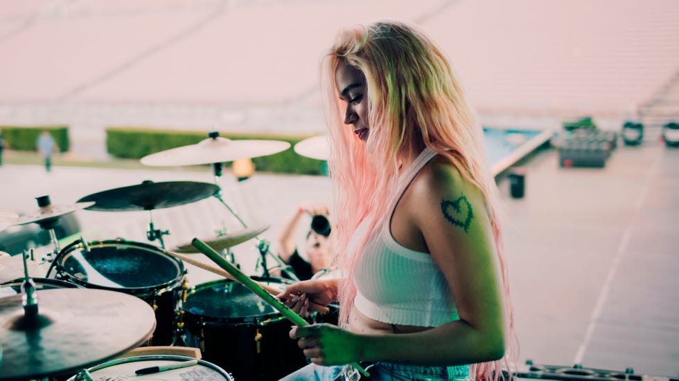 a woman with long hair plays the drums