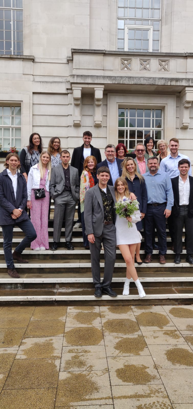 a bride in a mini dress and margiela tabis poses on the steps of the courthouse with her husband and family