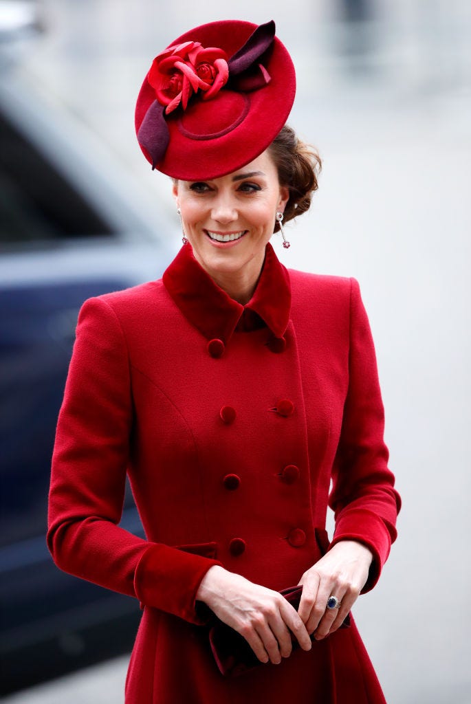 Kate, Duchess of Cambridge walks away from her car wearing a red jacket and matching hat