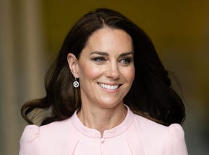 the princess of wales smiling as she walks to an engagement, she is wearing a pale pink jacket and earrings