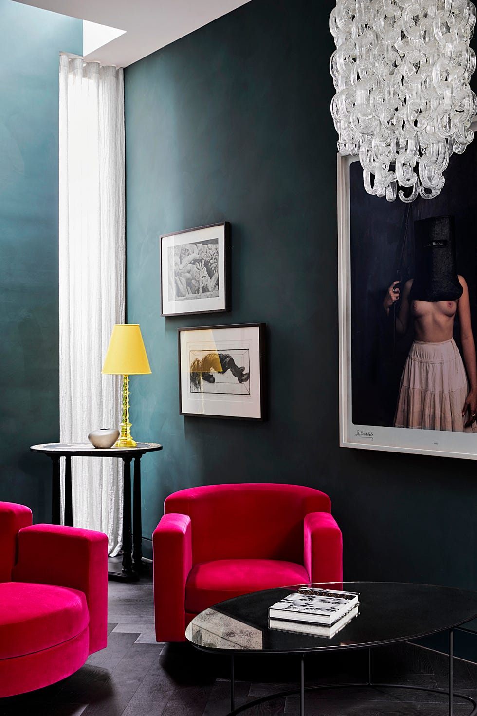moody living room with dark teal walls and two fuchsia armchairs