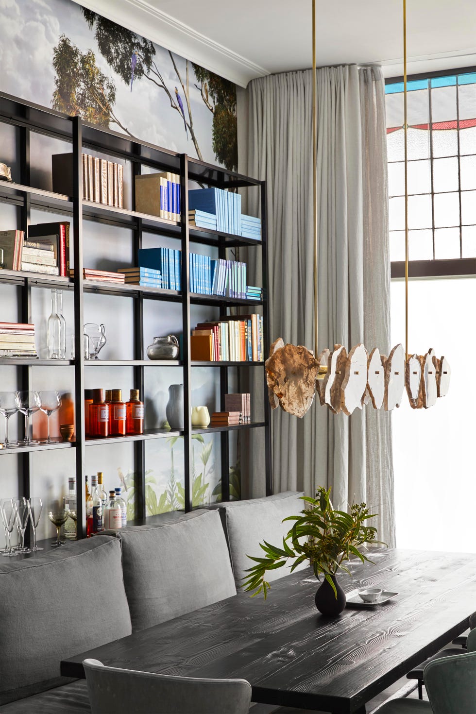 dining table surrounded by bookshelf and tropical wallpaper