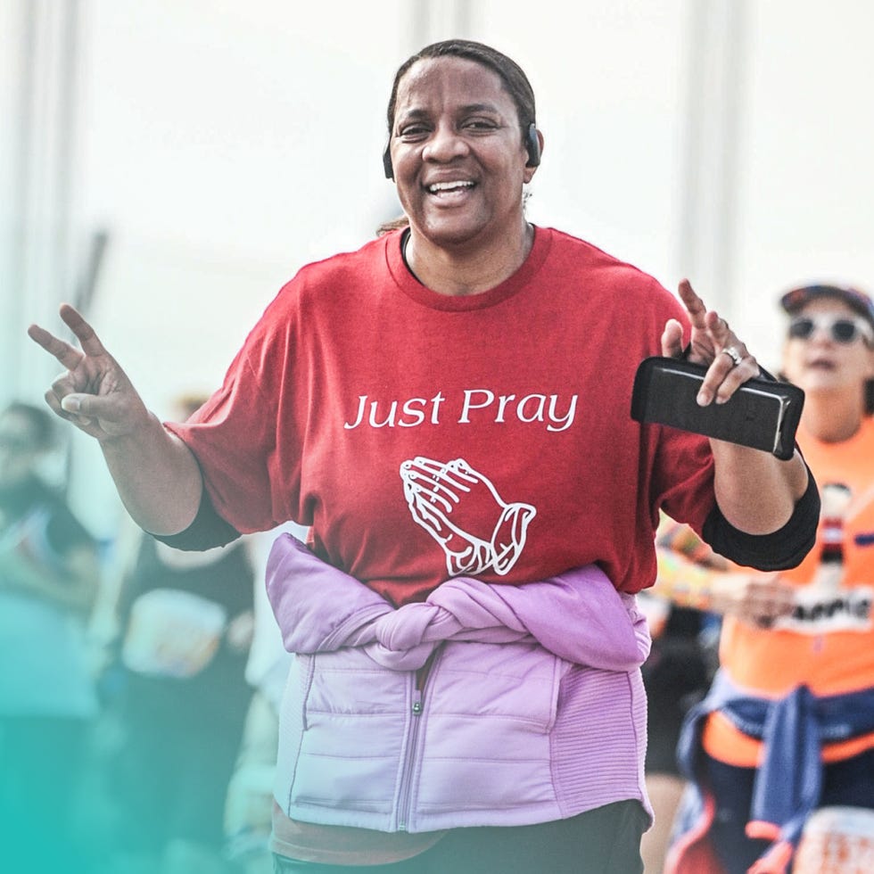 person wearing a red tshirt with just pray text and praying hands graphic making a peace sign