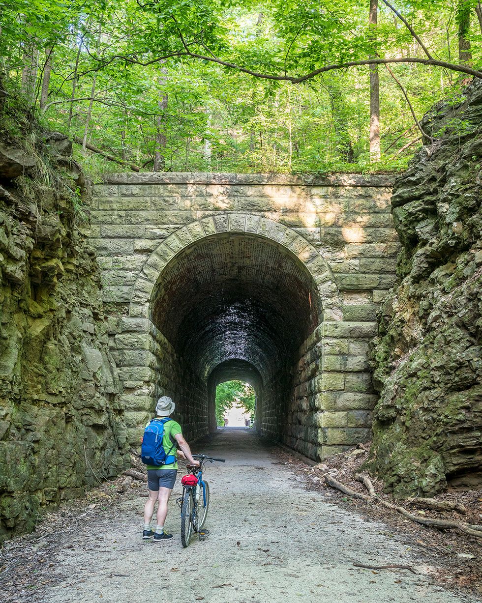 biker entering stone tunnel on gravel katy trail in missouri