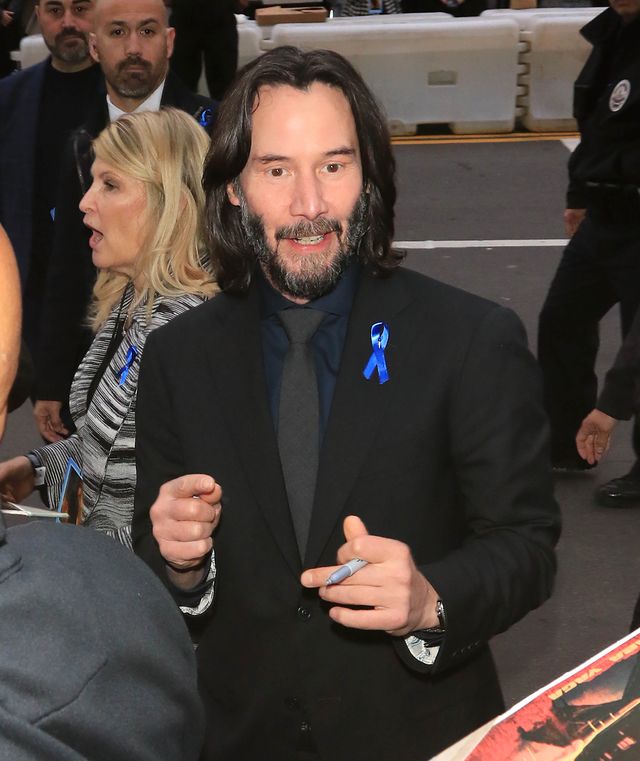 keanu reeves smiling while holding a marker to sign autographs