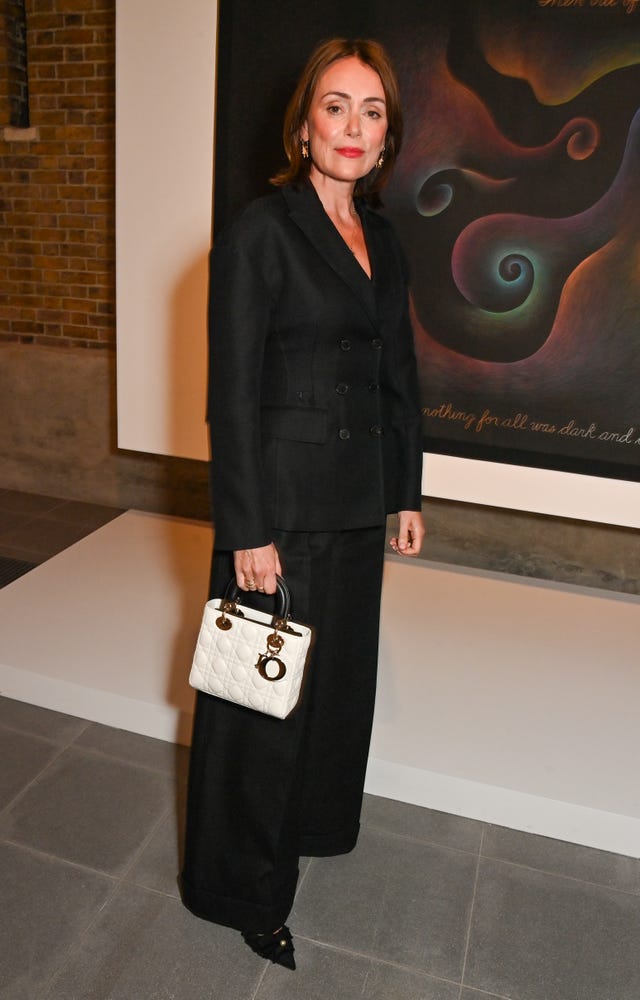 keeley hawes in a black suit holding a white handbag