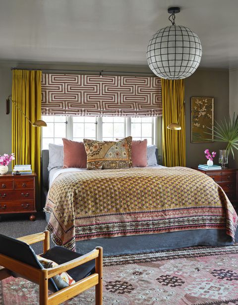 in the owners bedroom an antique carpet pillow is on the bed and the rest of the room has a boho vibe