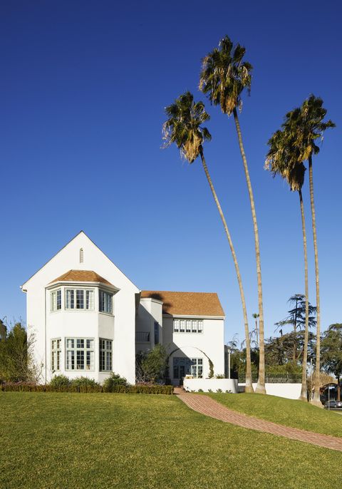 a white two story house with four tall palm trees out front