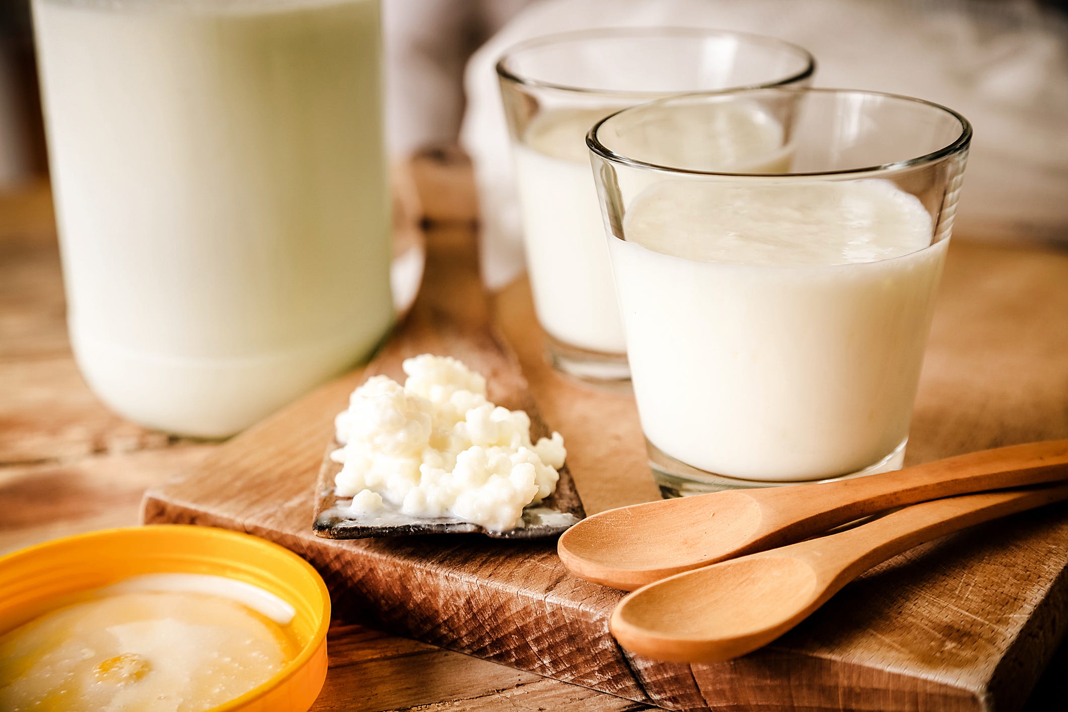 Kefir Grains In Wooden Spoon With Glass Of Kefir