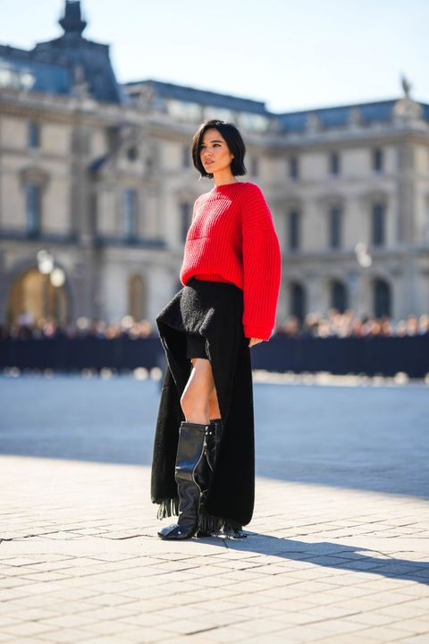 paris, france   october 04 kelsey asbille wears a red ribbed wool oversized pullover, a black felt asymmetric long train skirt from louis vuitton, black shiny leather block heels patti knees boots  high boots from louis vuitton, outside louis vuitton, during paris fashion week   womenswear springsummer 2023, on october 04, 2022 in paris, france photo by edward berthelotgetty images