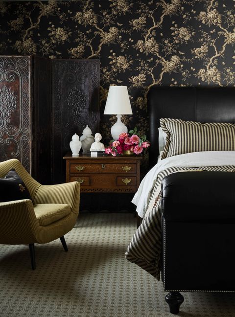 a bed is upholstered in motorcycle leather and trimmed with aged brass nailheads and the room is mostly black and gold