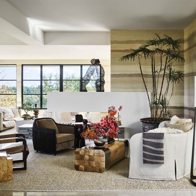huge windows in the corner of the room let in natural light and the room is decorateed with mostly warm neutral colors