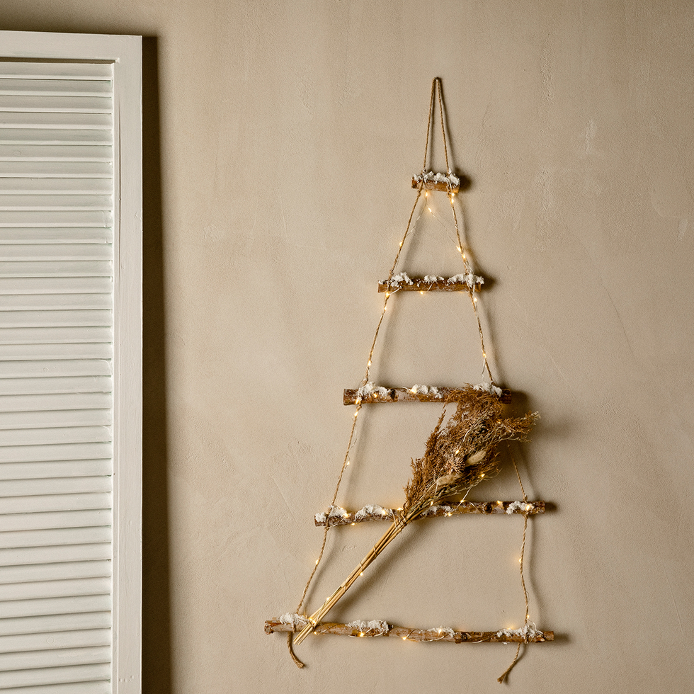 arbol de navidad hecho con ramas para colgar en la pared