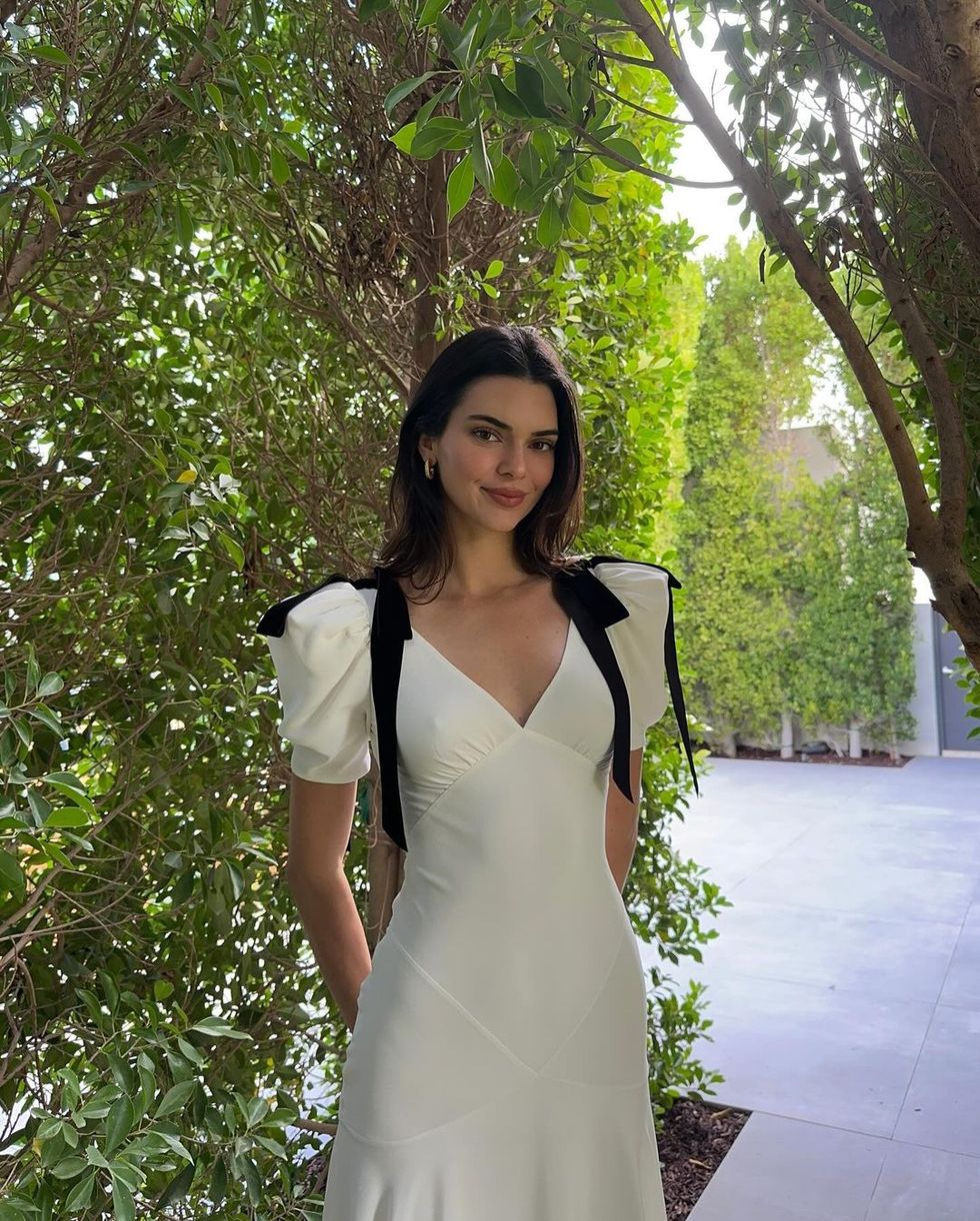kendall jenner wearing a white coquette dress with black ribbons in a garden for easter