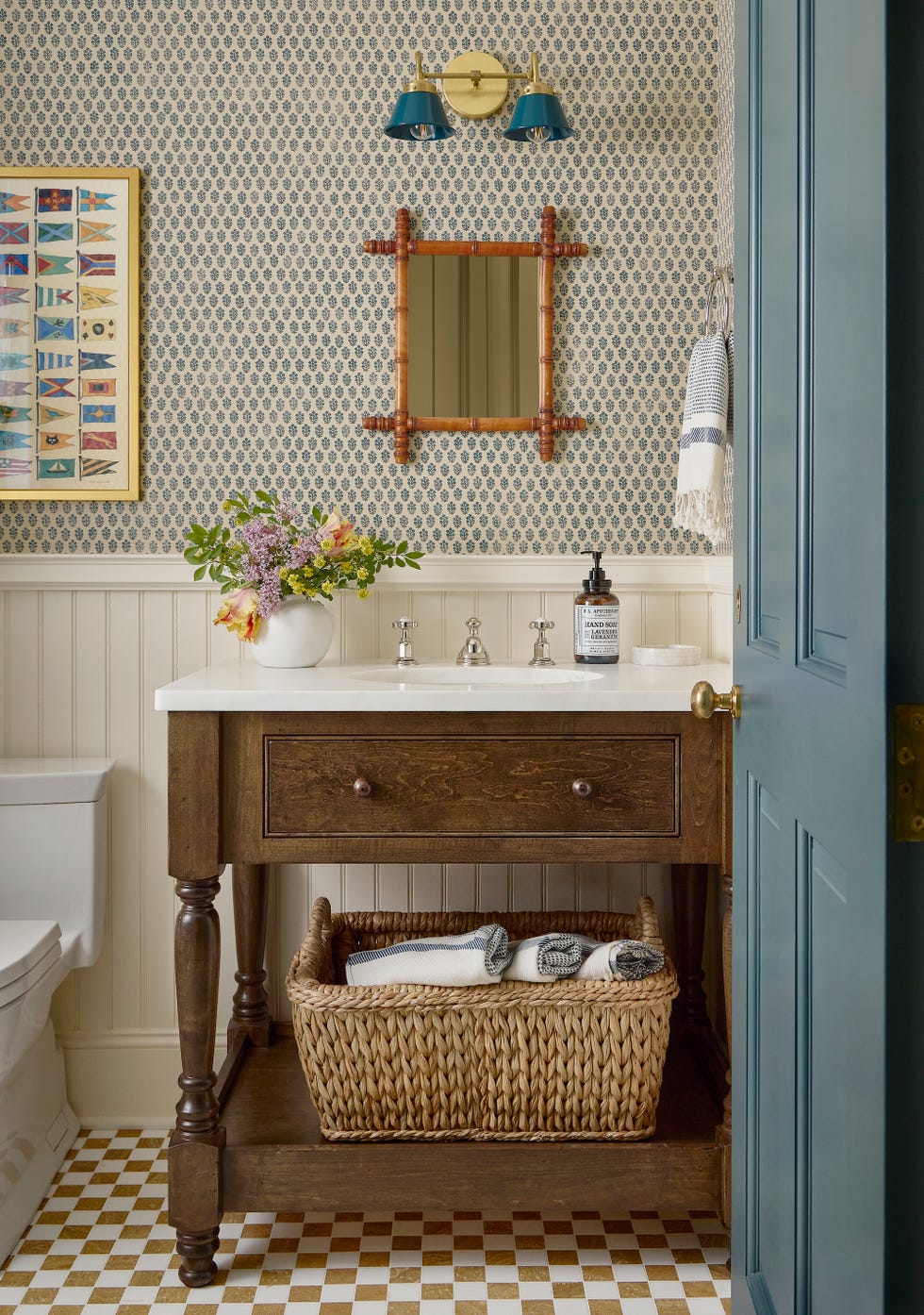 bathroom with wood vanity with basket underneath and a small mirror and lights above the sink