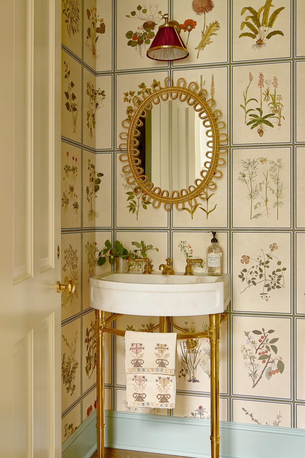 powder bathroom with botanical wallpaper and slender sink and metallic mirror