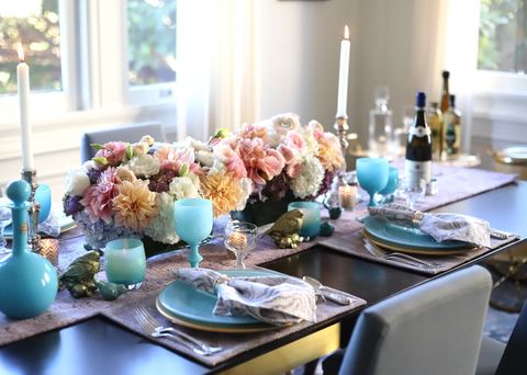 a table set with flowers, blue glasses and plates, colorful napkins and candlesticks