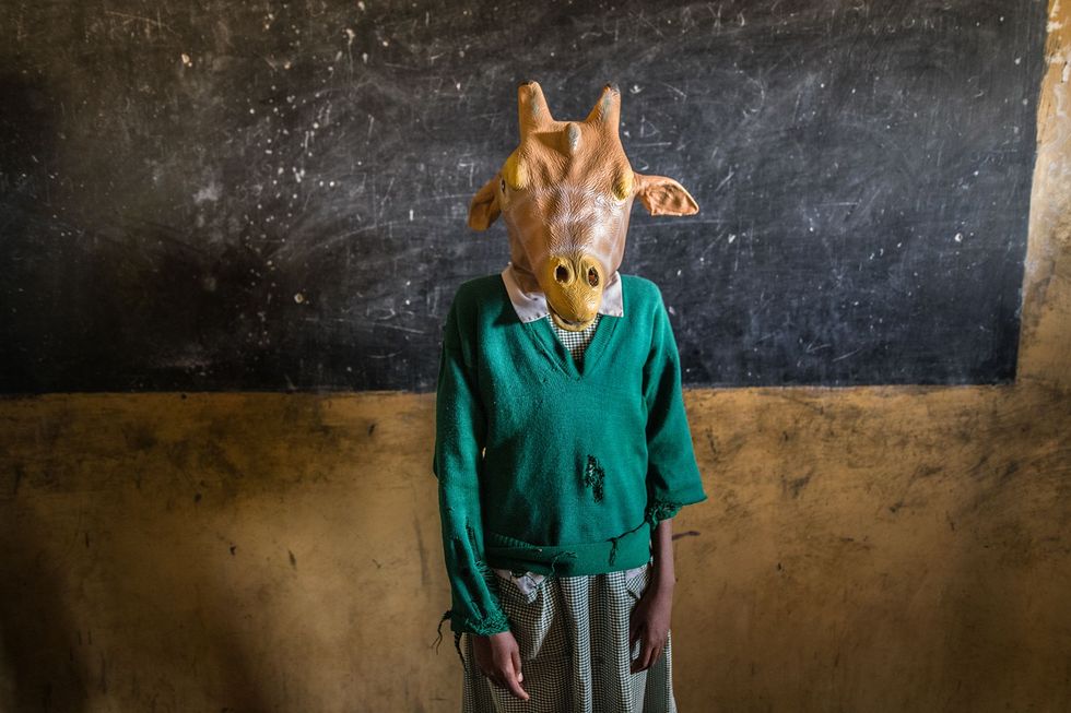 In Kenia zet een leerling een giraffenmasker op bij een bezoek van de Twiga Walinzi giraffenopzichters Deze natuurbeschermingsorganisatie geeft de kinderen les over giraffen in de hoop dat ze later de dieren zullen helpen beschermen
