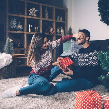 a man and woman sitting next to a christmas tree