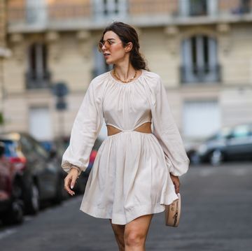een vrouw loopt op straat in parijs in een wit jurkje