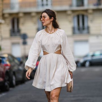 een vrouw loopt op straat in parijs in een wit jurkje