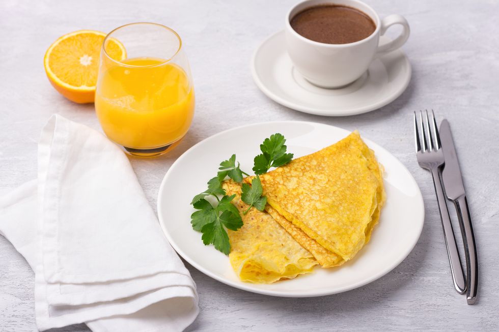 keto breakfast high fat low carb, pancakes without flour and nuts, ketocoffee bulletproof with coconut oil, freshly squeezed orange juice and orange on a light gray background