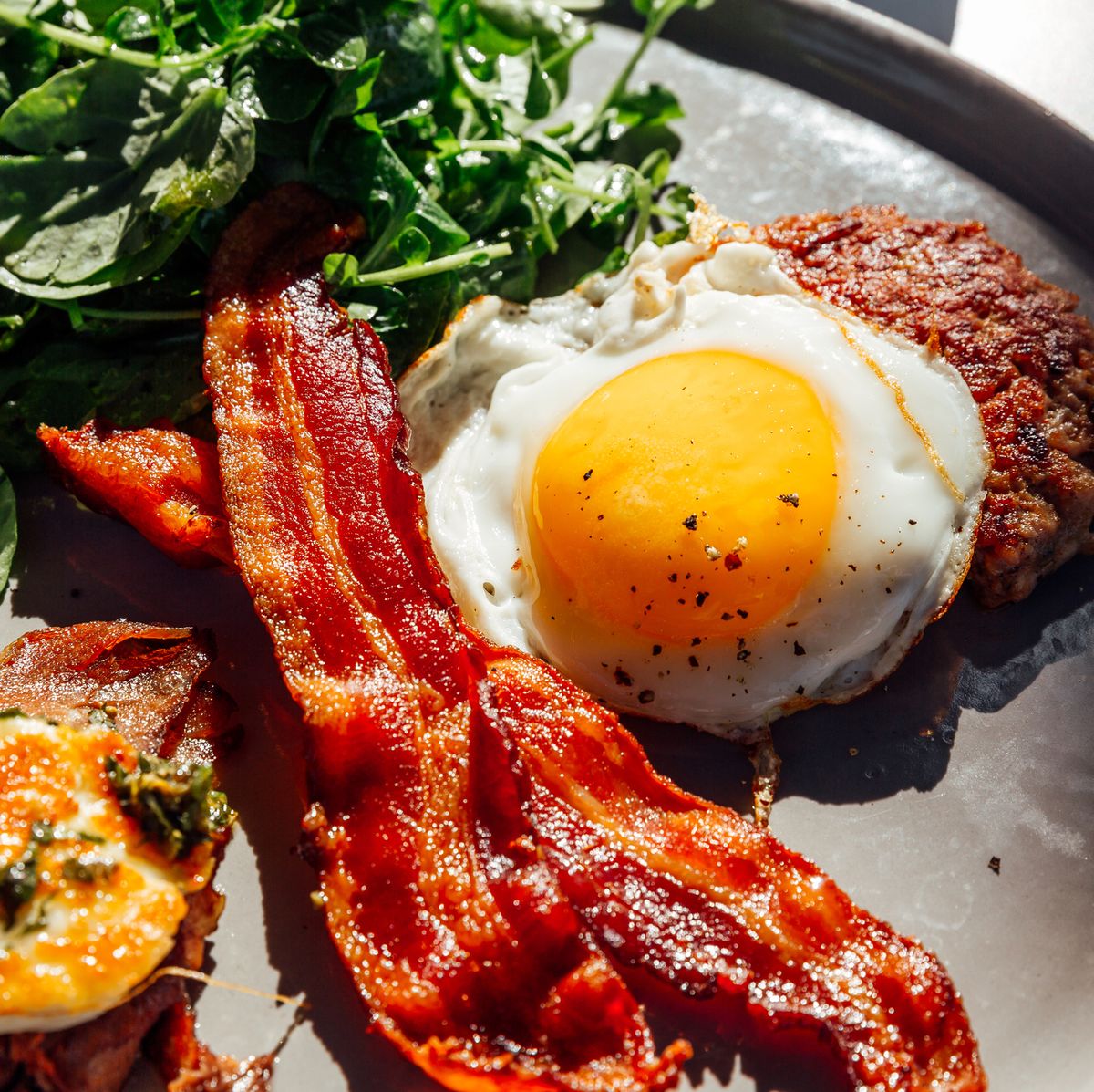 https://hips.hearstapps.com/hmg-prod/images/keto-breakfast-with-fried-egg-bacon-cheese-ground-royalty-free-image-1692619276.jpg?crop=0.668xw:1.00xh;0.167xw,0&resize=1200:*