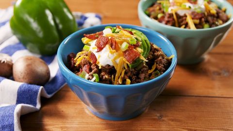 keto chili topped with shredded cheese, sour cream, bacon, and avocado in a blue bowl