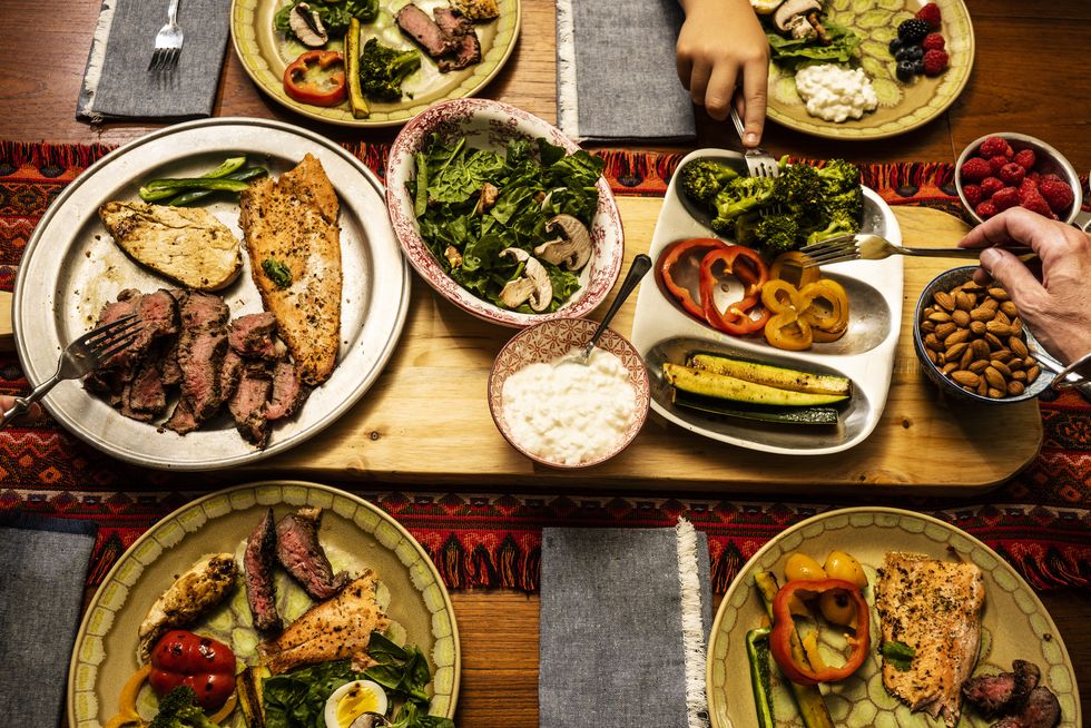 A ketogenic meal laid out on a dining table with the hands of people serving themselves