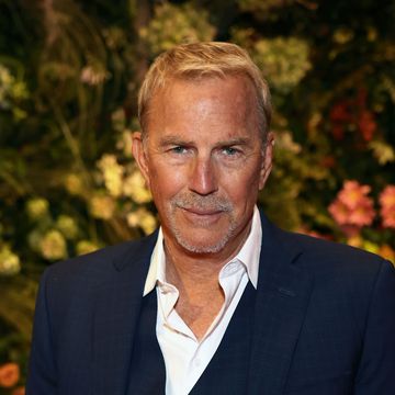 a man in a blue three piece suit and a white collared shirt smiles at the camera