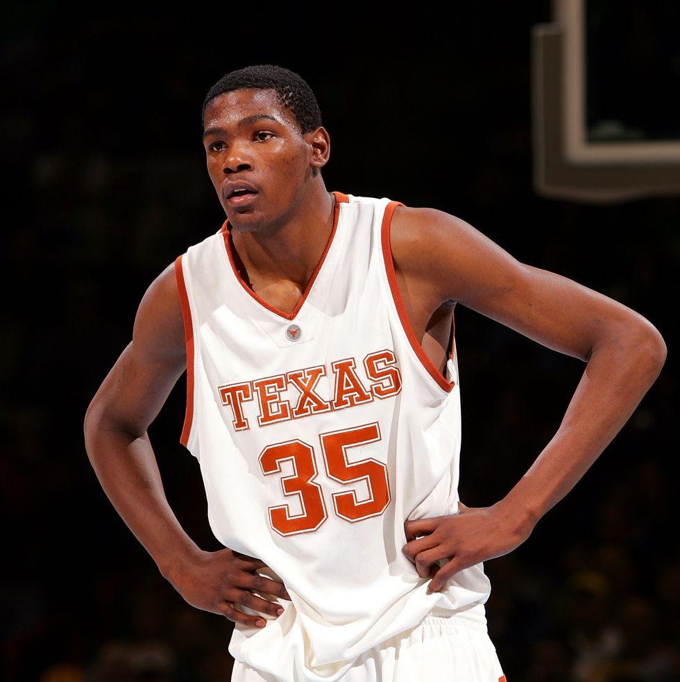 a man in a white and orange basketball jersey stands with hands on his hips