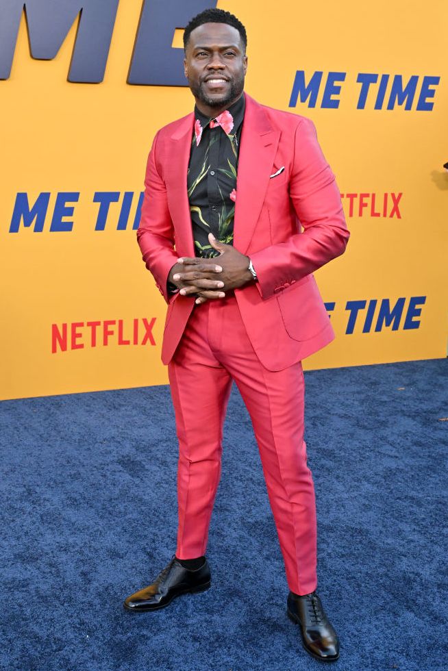 kevin hart posing for photos in a pink suit at a premiere event