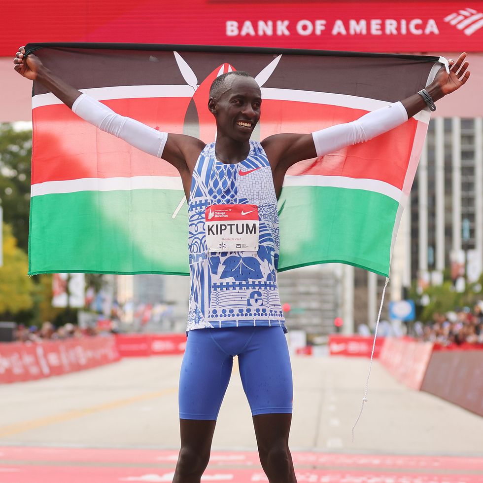 kelvin kiptum holds kenyan flag in front of marathon finish line in chicago in 2023
