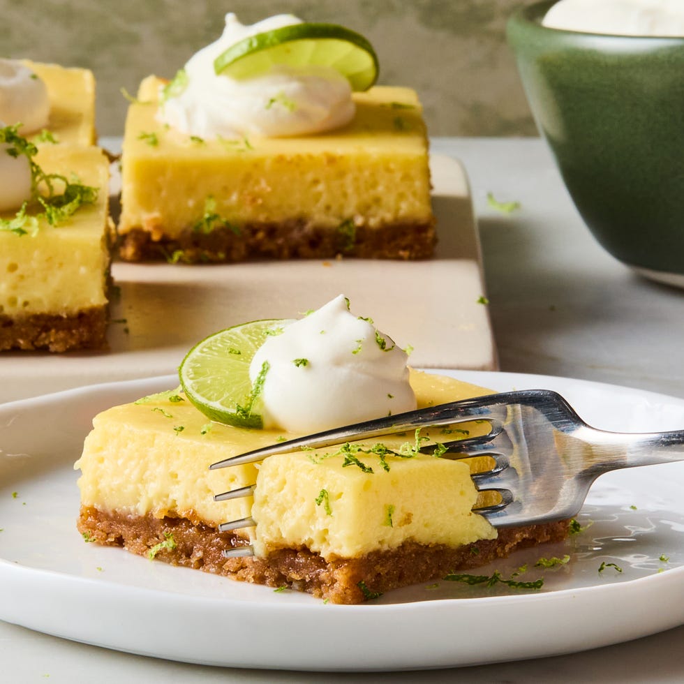 key lime bars topped with whipped cream, a lime zest, and a lime wedge