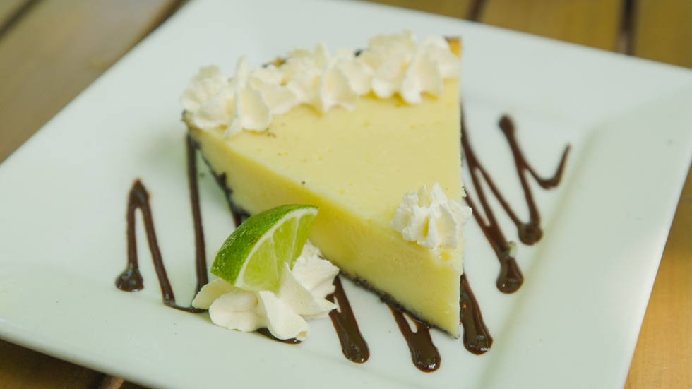a slice of cake with white frosting and a slice of lime