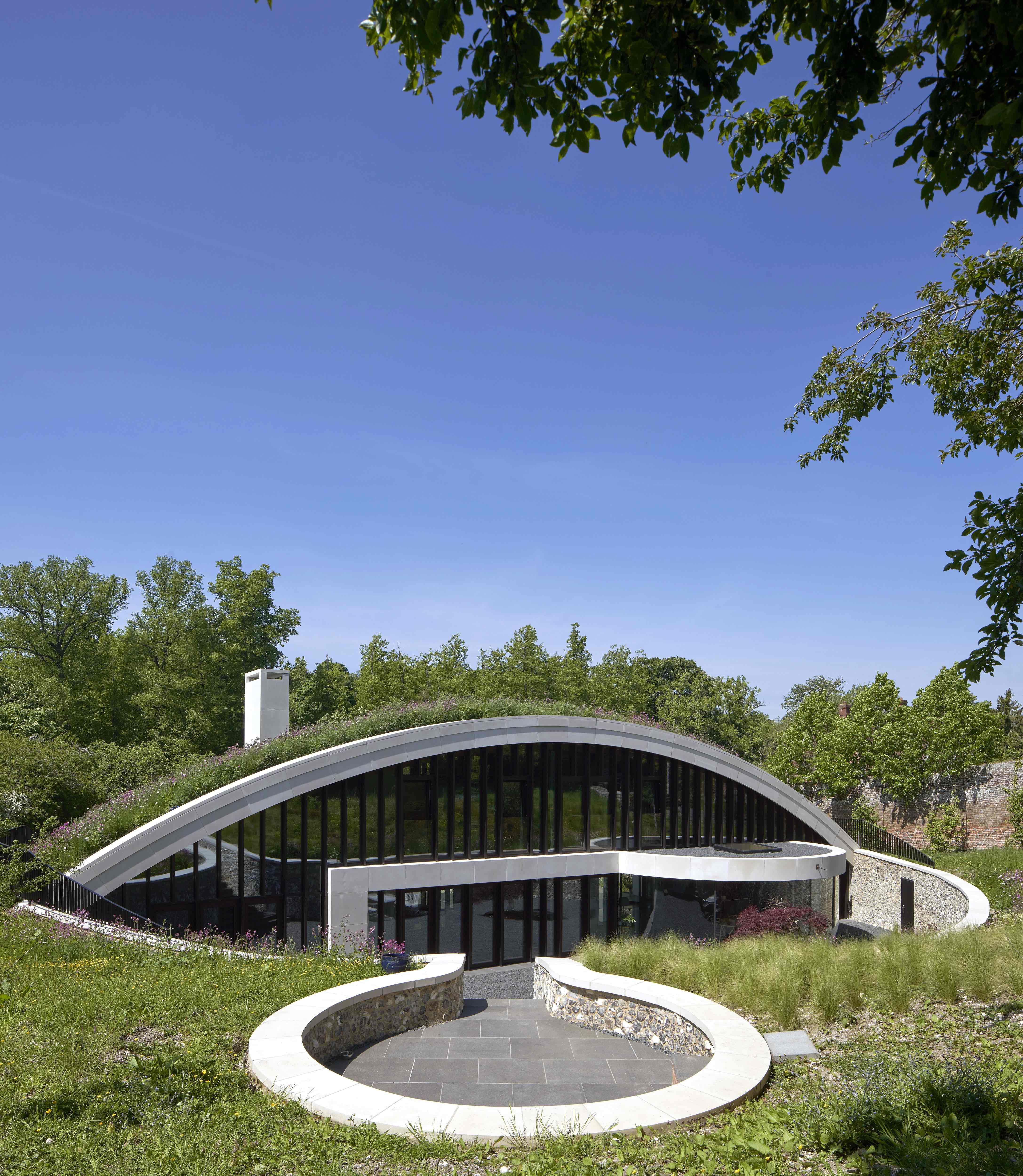 DDM Architectuur designs stone and glass home overlooking a pond