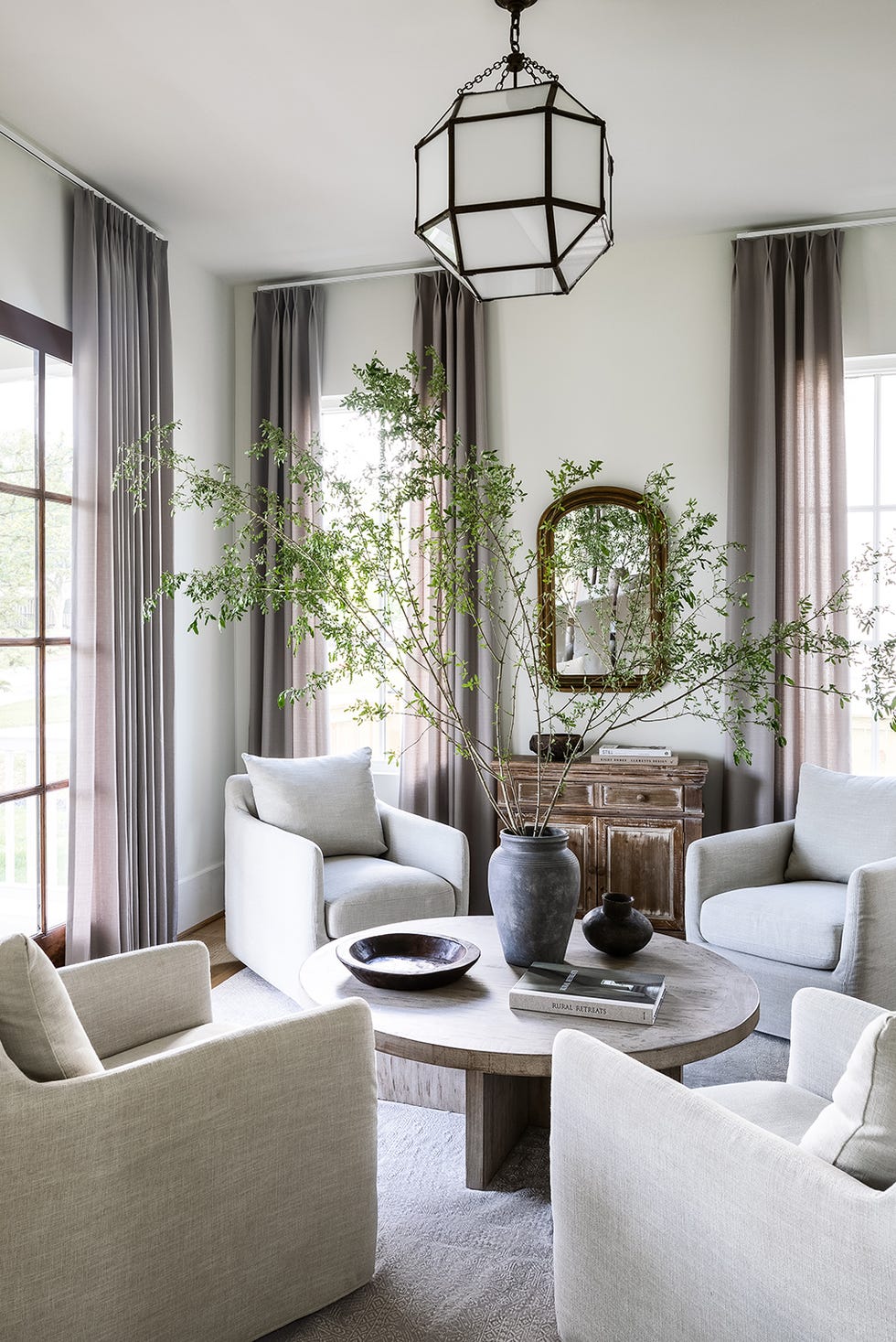 a living room with a chandelier and a table and plum brown curtains