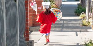 kid graduate carrying balloon and flowers