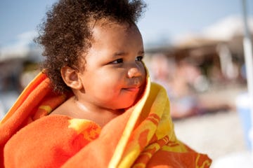 baby wrapped in orange and yellow beach towel